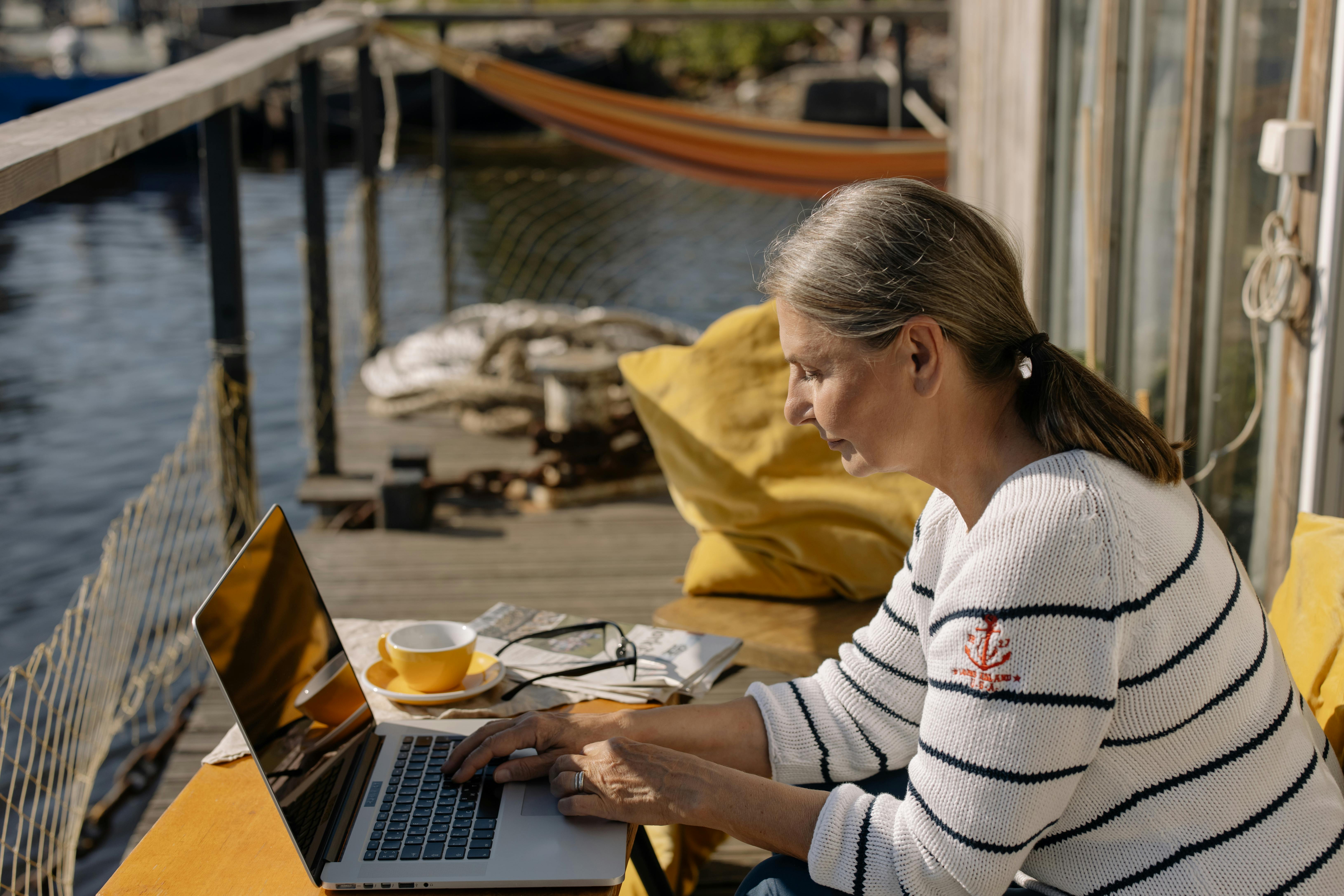 Dame sidder ved computer ved vandet